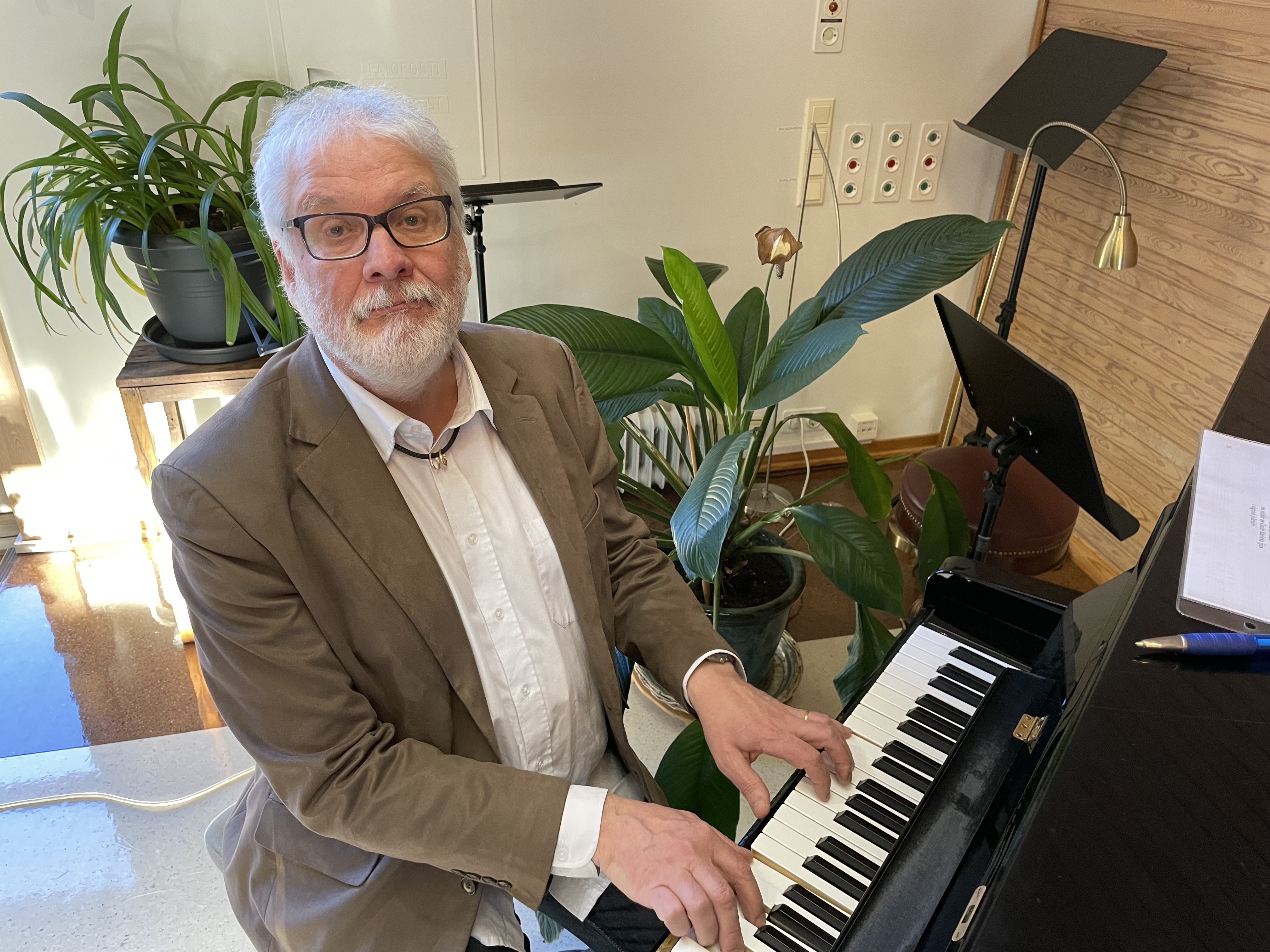 Bild av körledaren Roland Näse vid pianot i Ekenäs församlingshem.