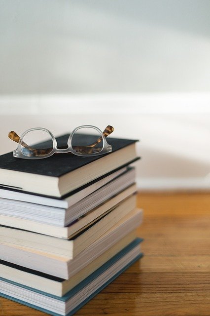 En hög med böcker och ett par glasögon.